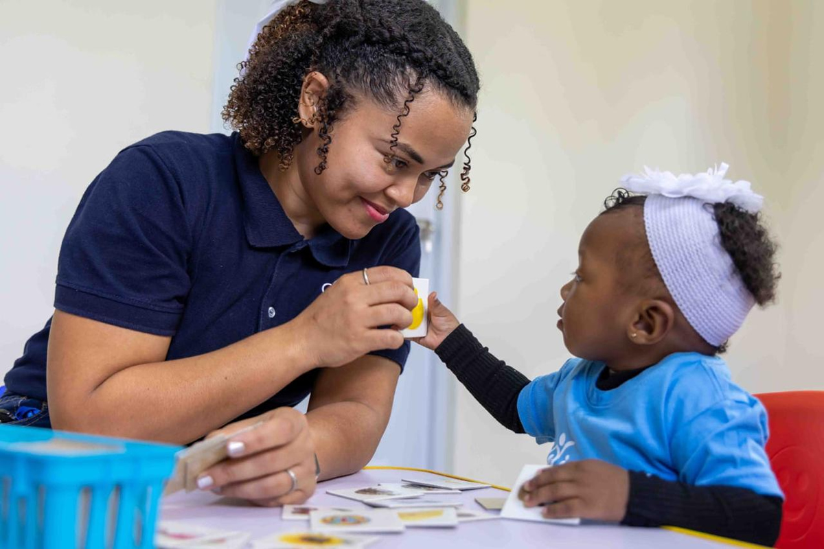 Colaboradora del INAIPI junto a niña en el aula del Centro