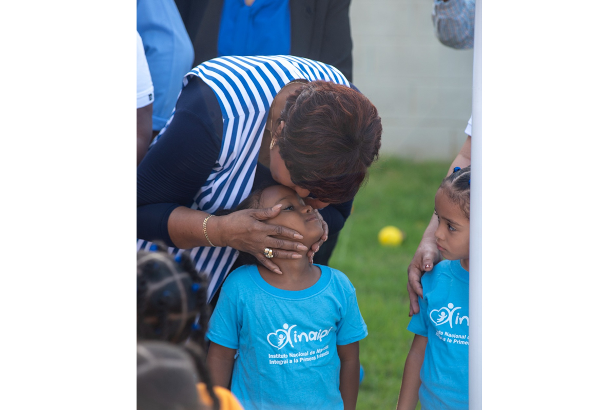 Josefa Castillo Rodríguez, directora del INAIPI, le da un beso en la frente a un niño durante la apertura de los servicios